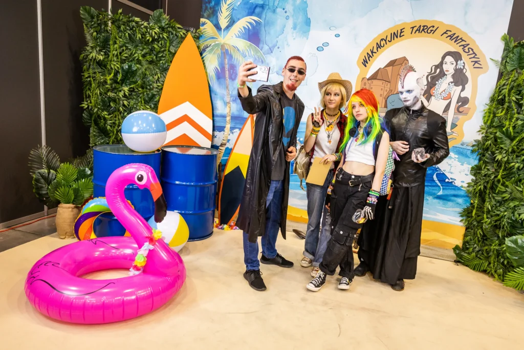 Ludzie na tle ścianki Wakacyjnych Targów Fantastyki
