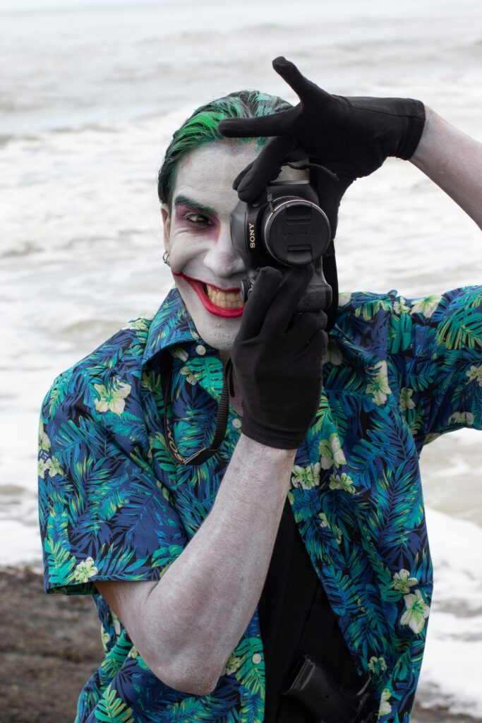 Joker z Batmana w koszuli w kwiatki i z aparatem